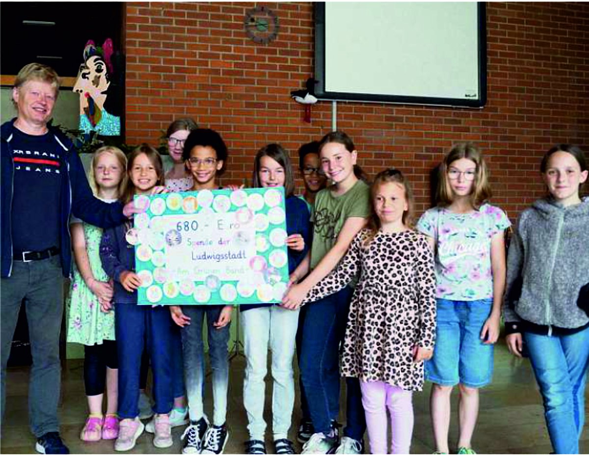 Auf dem Bild ist eine Gruppe von Schülerinnen und Schülern der 4. Klasse zu sehen, die einen Scheck an den Leiter des Tierschutzvereins Kronach überreichen.