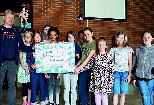 Auf dem Bild ist eine Gruppe von Schülerinnen und Schülern der 4. Klasse zu sehen, die einen Scheck an den Leiter des Tierschutzvereins Kronach überreichen.