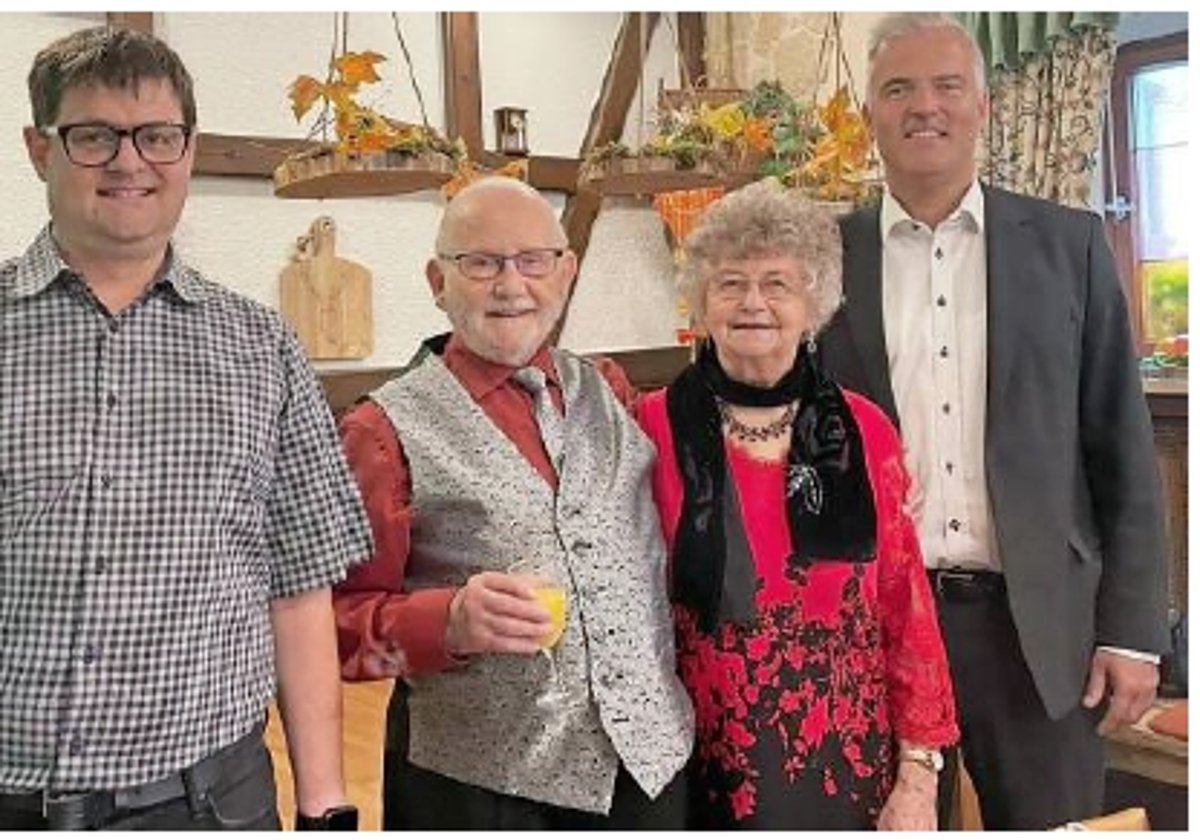 Dat Foto zeigt den Jubilar in der Mitte. Daneben steht eine ältere Frau und zwei Männer, darunter BGM Timo Ehrhardt. Sie alle lächeln in die Kamera. 