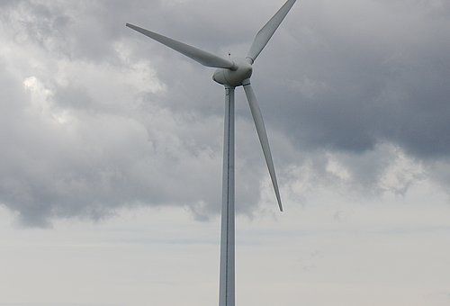 Das Bild zeigt ein Windrad vor einem stark bewölkten Himmel