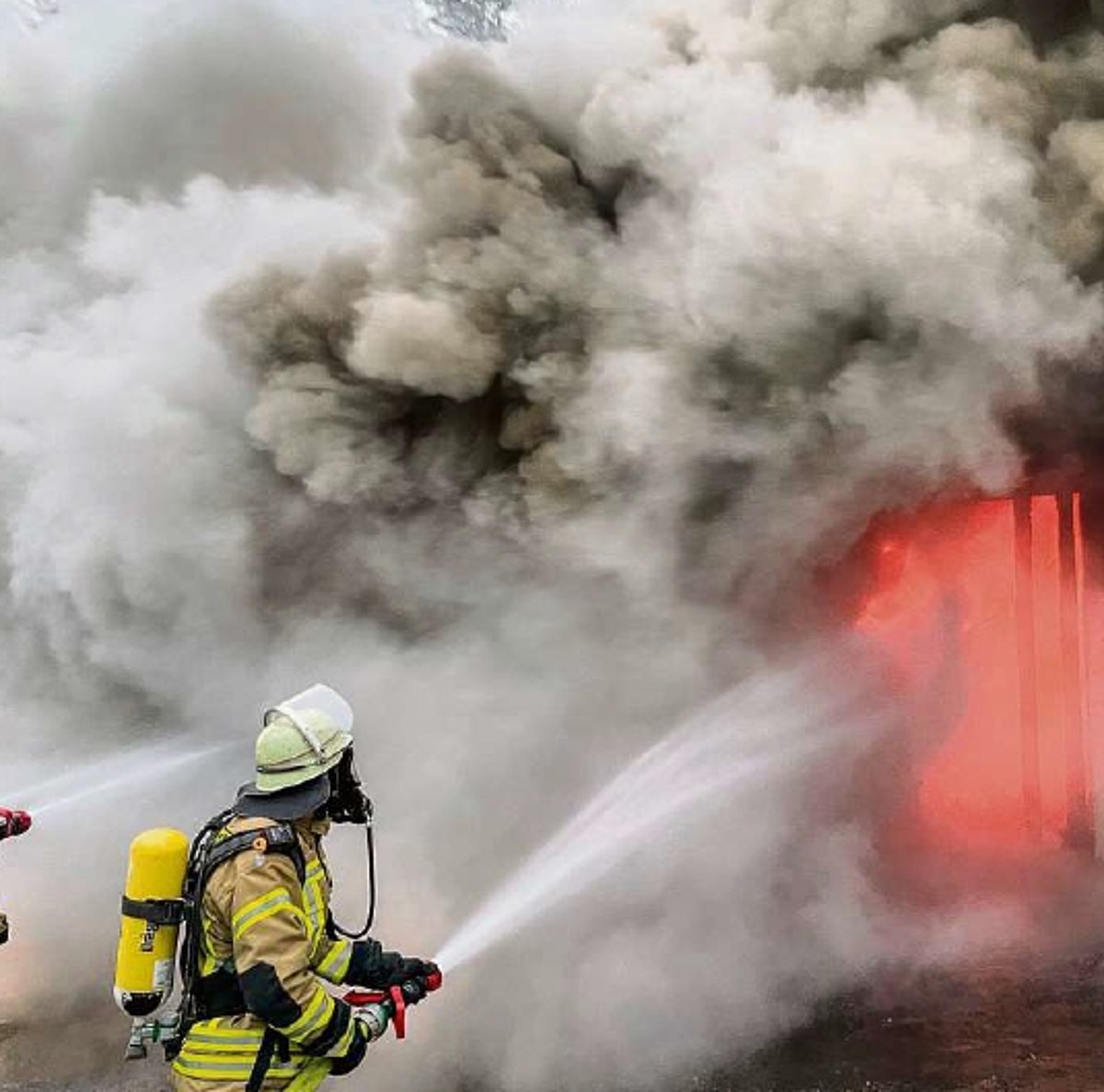 Ein Feuerwehrmann in Schutzanzug löscht ein Feuer