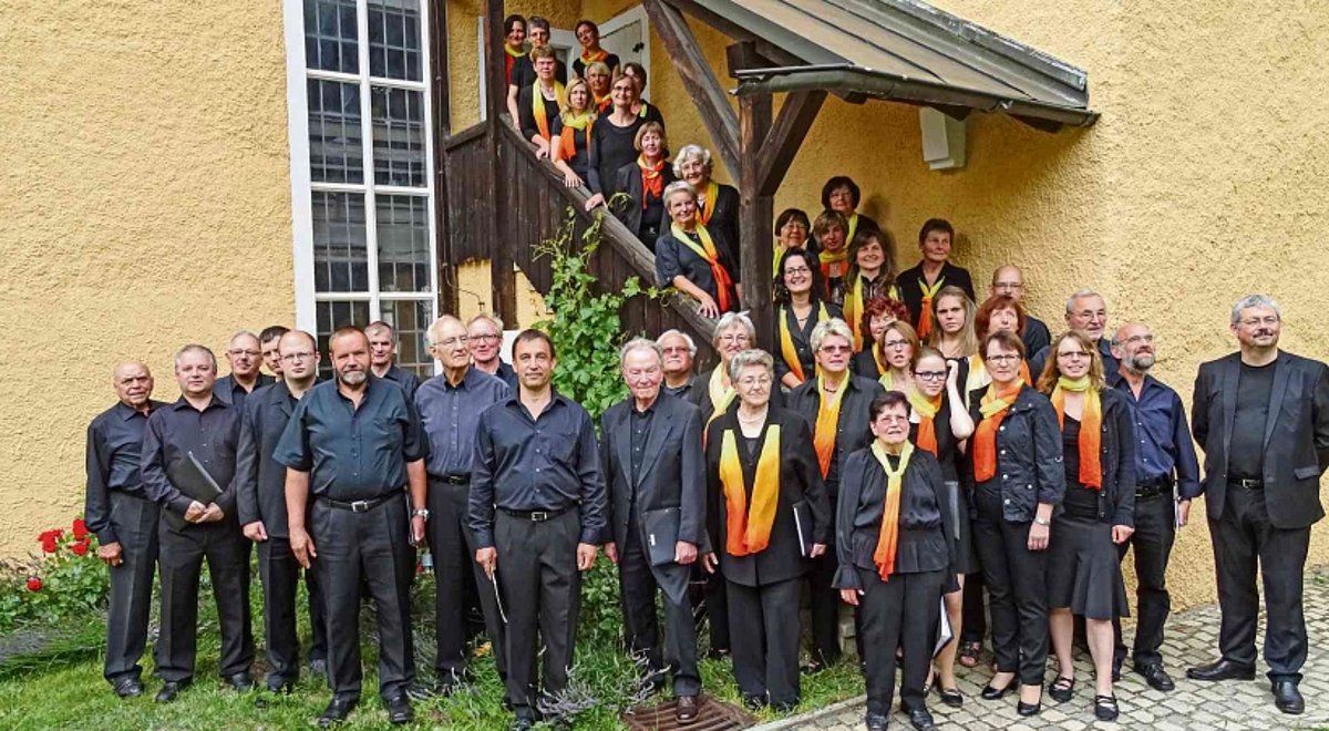 Männer und Frauen stehen in einer Gruppe an einer Kirche