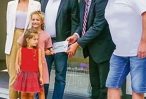 Das Foto zeigt drei Männer darunter Bürgermeister Timo Ehrhardt, eine Frau und zwei Mädchen. Eines der Mädchen übergibt ein Schild an den Bürgermeister. Alles lachen in die Kamera. 