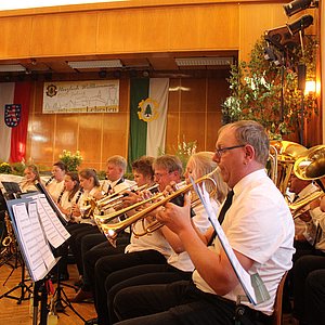 Im Halbkreis sitzen die Musiker des Orchesters "Glück auf". Das Foto zeigt sie während sie ein Musikstück spielen.