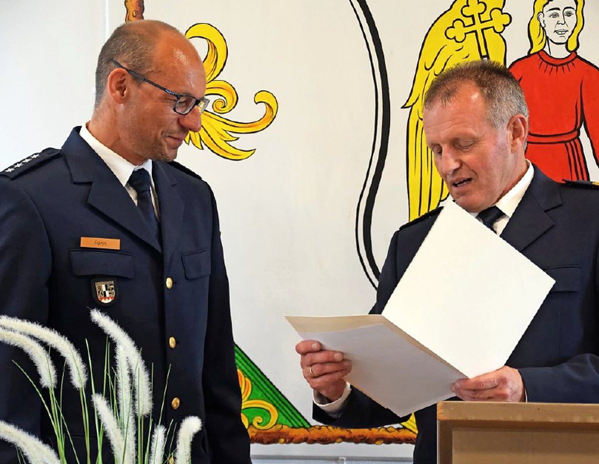 Zwei Polizisten in Uniform. Der eine liest aus einer weißen Mappe etwas vor, der andere ist der neue Leiter der Polizeiinspektion Ludwigsstadt. Er hört gespannt zu. 