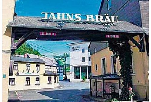 ein Tor aus Holz zwischen zwei Häusern zeigt den Eingang zu einem Betriebsgelände. Auf dem Dach des Tores steht "Jahns Bräu".